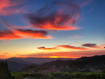 Scenic view of dramatic sky over silhouette landscape during sunset