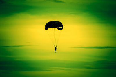 Low angle view of person paragliding against sky during sunset