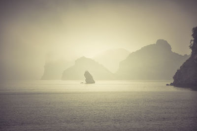 Mountains in sea against sky during sunset