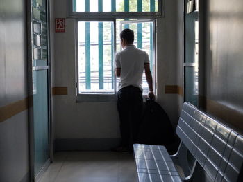 Rear view of man looking through window