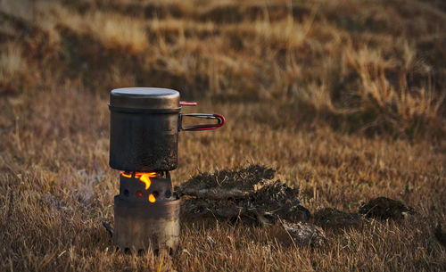 Close-up of fire on field with cow dunk and pot cooking