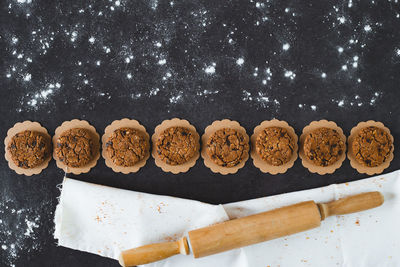 Directly above shot of chocolate chip cookies and rolling pin on black background