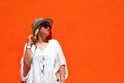 Woman standing against orange wall