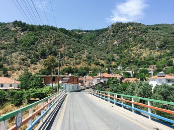 Road amidst trees and buildings against sky