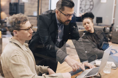 Manager using laptop while discussing with businessman in office