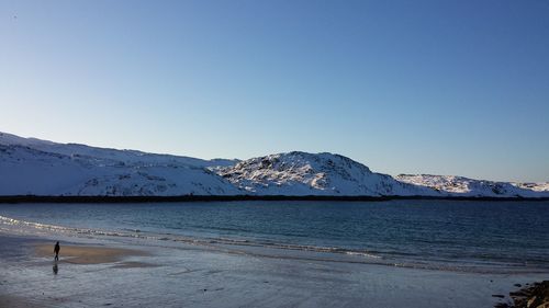 Scenic view of sea and mountains against clear blue sky