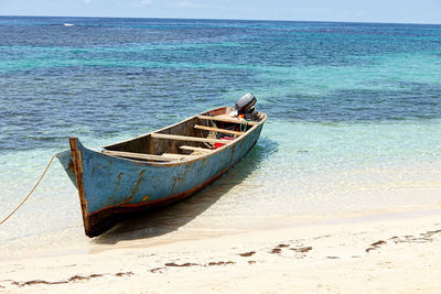Boat moored on beach against sky