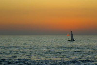 Sailboat sailing in sea against sky during sunset