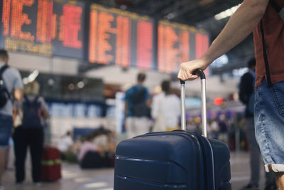 Traveling by airplane. man waiting in airport terminal. selective focus on hand holding suitcase.