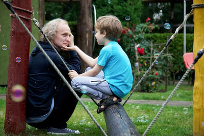 Mature man and grandson crouching in playground