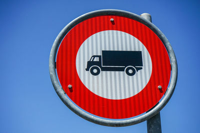 Close-up of road sign against blue sky