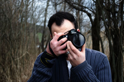 Young man photographing through camera in forest