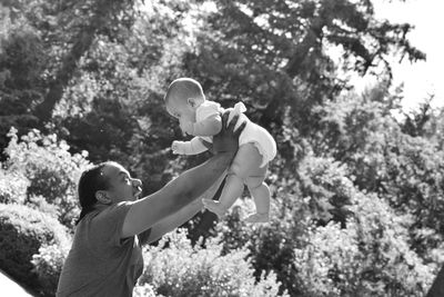 Rear view of father and son against trees