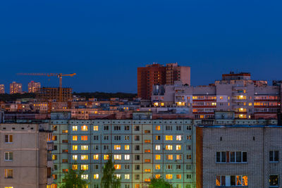 Illuminated buildings against blue sky at dusk