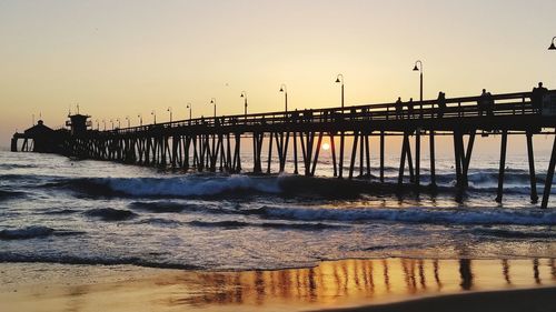 Pier over sea against clear sky during sunset