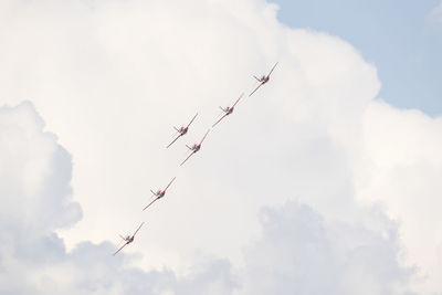 Low angle view of airshow against cloudy sky