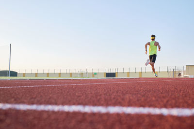 Young man trains running on new and red tracks