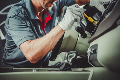 Midsection of man cleaning car in garage