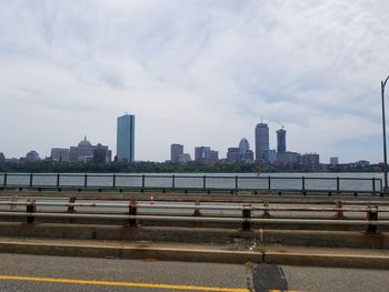 Bridge over river by buildings against sky in city