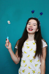 Portrait of happy woman holding toy against blue background