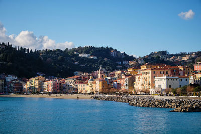 Townscape by sea against blue sky