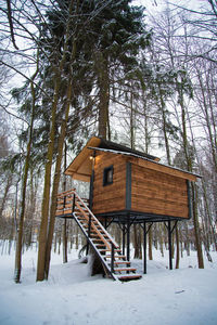 Built structure on snow covered field by trees