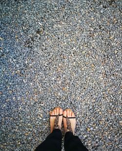 Low section of woman standing on pebbles