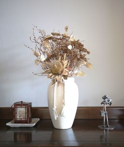 Close-up of white flower vase on table against wall at home