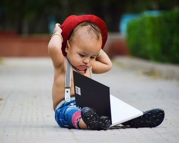 Close-up of cute boy with book sitting outdoors