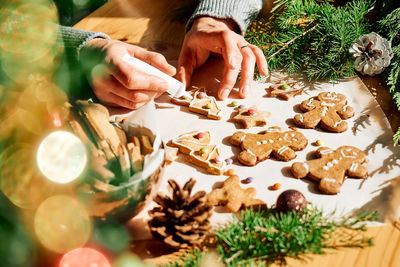 Woman's hands decorating glazed christmas gingerbread cookies.