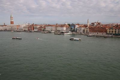 View of buildings at waterfront against cloudy sky