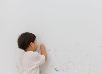 Rear view of boy writing on wall