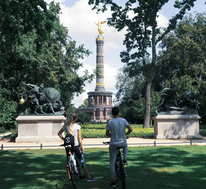 Rear view of friends with bicycles looking at statue