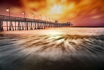 Pier over sea against sky during sunset