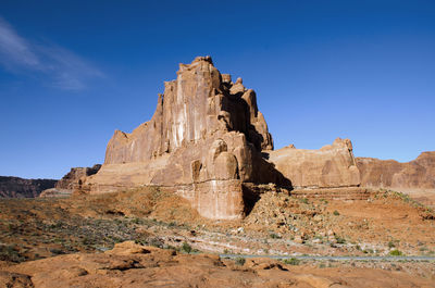 Low angle view of rocky mountain against blue sky