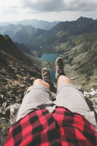 Low section of man lying on cliff against mountains