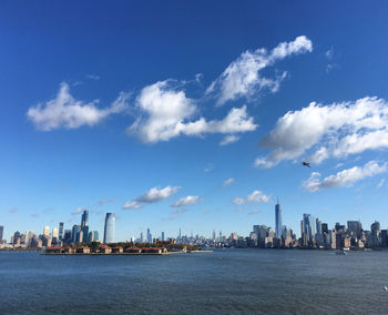 City at waterfront against cloudy sky