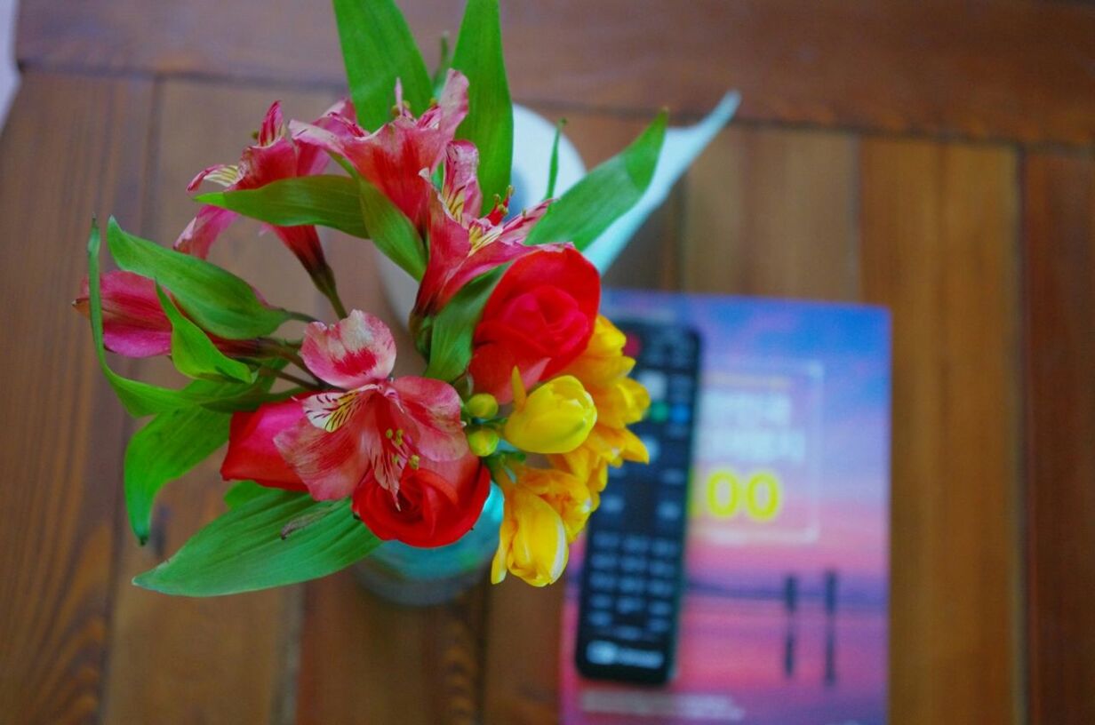 indoors, flower, freshness, table, petal, close-up, focus on foreground, multi colored, flower head, decoration, fragility, home interior, vase, yellow, still life, no people, red, selective focus, wood - material, day