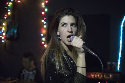 Young woman singing at band rehearsal