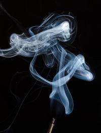 Close-up of smoke over incense against black background