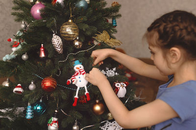 Girl decorating christmas tree at home