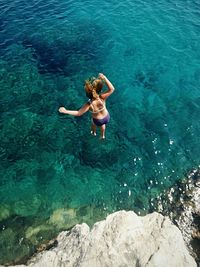 High angle view of woman wearing bikini jumping in sea