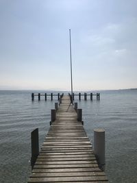 Wooden pier over sea against sky