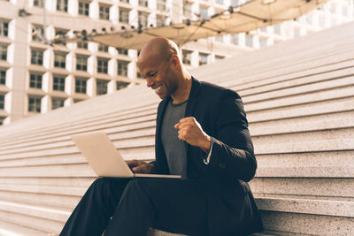 Young man using laptop while sitting on steps