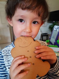 Portrait of cute girl eating gingerbread cookie at home