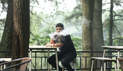 Couple sitting on bench by tree trunk