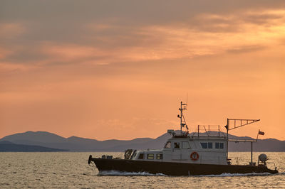 Sailboat sailing on sea against orange sky