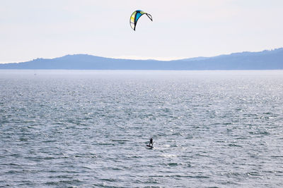 Person paragliding over sea against sky