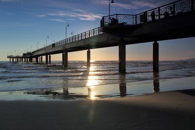 Bridge over sea against sky during sunset