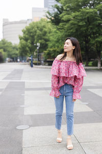 Full length of woman standing on road in city